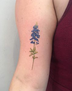 a blue flower tattoo on the left upper arm and right lower arm, which is covered in tiny blue flowers