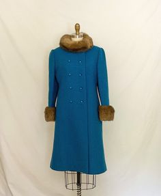 "One of my favorite finds ever! This coat is gorgeous and in wonderful condition. Thick wool turquoise blue outer later, double breasted with pretty diamond-shaped buttons. Fur on the collar and cuffs is real, probably mink, very soft. Collar fastens with hidden snaps and a hidden toggle at the left shoulder. Side pockets. Fully lined in blue satin. Half-belt (or Martindale) with buttons at the back waist. There are no tags, though this seems professionally made. Placing it some time in the sixt Turquoise Long Sleeve Winter Outerwear, Turquoise Long Sleeve Outerwear For Winter, Fitted Turquoise Outerwear For Winter, Coat With Fur Trim, Blue Wool Coat, Medium Coat, Coat With Fur, Thick Wool, 60s Mod