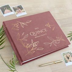 a wedding album on a table with some photos and pen next to it, surrounded by greenery