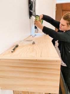 a woman using a power drill on a piece of wood