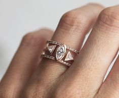 a woman's hand with a diamond ring on top of her finger and the other hand holding an engagement ring