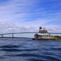 a light house sitting on top of a small island in the ocean next to a bridge