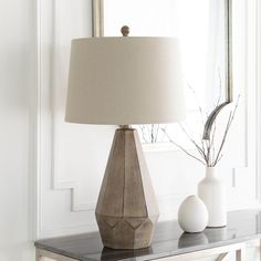 two vases sitting on a table with a lamp in front of them and a mirror behind it