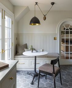 a table with two chairs and a bench in a room that has white paneling on the walls