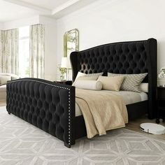 a large black bed sitting in a bedroom next to a window