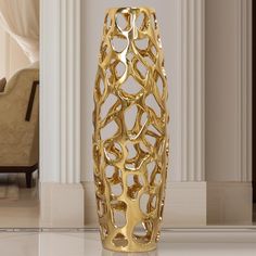 a gold vase sitting on top of a white floor next to a chair and table