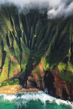 an aerial view of the mountains and ocean with clouds in the sky over them, as seen from above