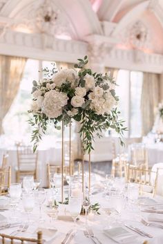 there are many flowers in tall vases on the long table at this wedding reception