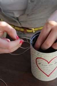 a woman is holding thread in a can with a heart painted on the side and writing on it