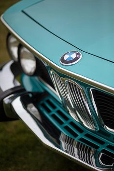 the front end of a blue bmw car with chrome grills and emblem on it