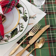 a place setting with plaid napkins and goldware