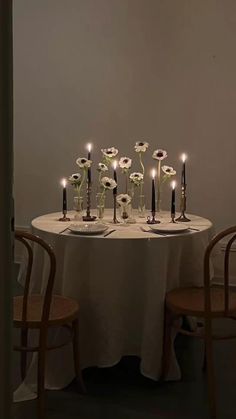 a table topped with lots of white flowers next to two chairs and a vase filled with candles