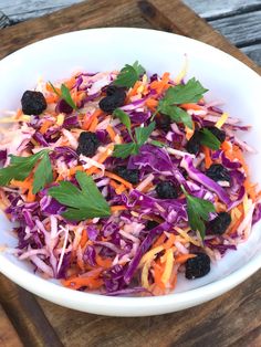 a white bowl filled with coleslaw and carrots on top of a wooden table