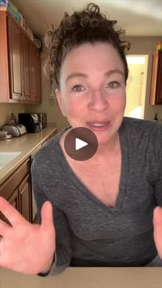 a woman sitting at a kitchen table with her hands in the air