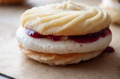 two cookies with jam on them sitting on top of a piece of waxed paper