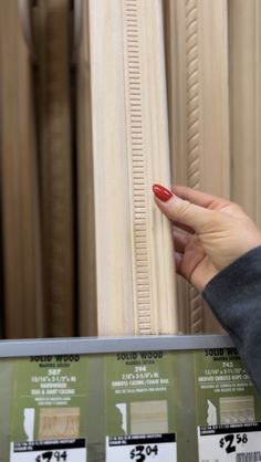 a woman's hand is pointing at the base of a column in a store