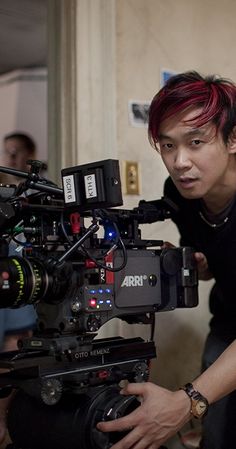 a man with red hair is looking at a camera set up in front of him