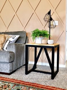 a grey couch sitting next to a table with a potted plant on top of it