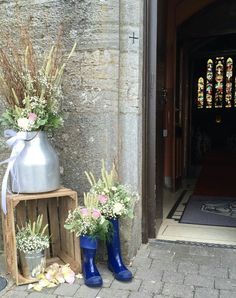 two vases with flowers are sitting next to each other on the side of a building