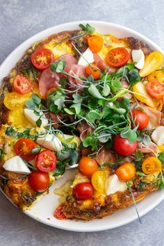 a pizza topped with lots of veggies on top of a white plate