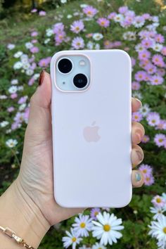 someone is holding their iphone in front of some daisies and wildflowers at the park