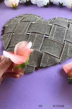 someone is making a heart shaped pillow out of fabric and flowers on the table next to it