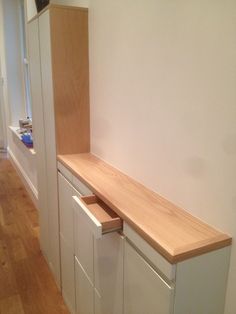 an empty room with white cabinets and wood flooring on the wall, next to a window