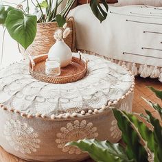 a plant sits on top of a round ottoman