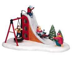 a figurine of children playing on a slide with snow and trees in the background