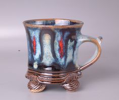 a blue and red coffee cup sitting on top of a white table next to a silver object