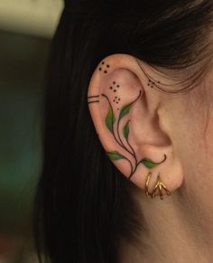 a close up of a person's ear with tattoos on it and flowers in the middle