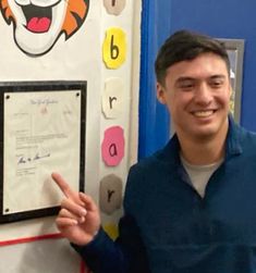 a man standing in front of a bulletin board with a tiger face on it's side