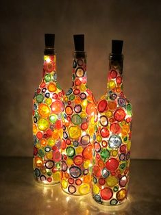 three glass bottles with lights inside them on a table