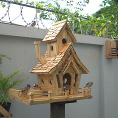 a bird house made out of wood with birds perched on the roof and around it