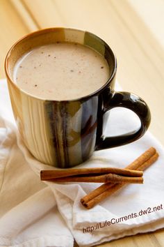 a cup of coffee and cinnamon sticks on a table