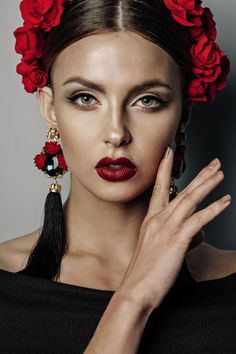 a woman with red lipstick and flowers in her hair is posing for the camera while holding her hand up to her face