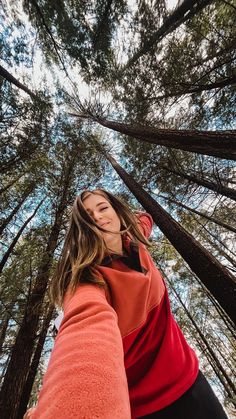 a woman standing in front of tall trees