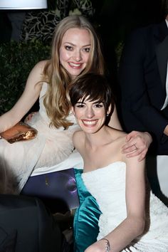 two women sitting next to each other at a formal event