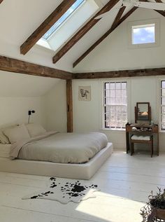 a bedroom with white walls and exposed wood beams on the ceiling is decorated with cow hide rugs