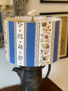 a lamp that is sitting on top of a wooden table with a blue and white lampshade