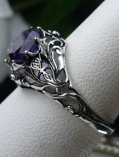 Natural Amethyst Ring Daisy Design#66 In Stock Size 6 Inspired by the Art Nouveau movement of the early 20th century, I now offer this lovely reproduction filigree ring in sterling silver. This gorgeous ring is set with a genuine/natural 1.5ct purple amethyst gemstone; which has a great shine and very good clarity. The round full cut purple amethyst gemstone is 8mm (5/16th of an inch) in diameter. The ring measures 12mm NS on the finger. The inside of the band is marked 925 for sterling. Notice Purple Amethyst Ring With Intricate Design For Promise, Purple Amethyst Promise Ring With Intricate Design, Purple Intricate Design Promise Ring, Purple Promise Ring With Intricate Design, Ornate Amethyst Purple Ring, Ornate Purple Amethyst Ring, Intricate Design Purple Amethyst Ring, Ornate Round Purple Amethyst Ring, Purple Amethyst Rings With Intricate Design