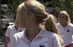 a group of women walking down a street next to each other in white polo shirts