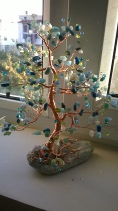 a tree made out of glass beads sitting on top of a table next to a window