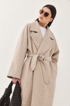 A heavy weight longline rode coat. An oversize fit with long voluminous sleeves and side pockets. Features a lapel collar with an embroidered logo. Comes with a detachable waist belt. A cozy worm coat you can wear over any outfit. 100% Polyester Color: Beige Care: Dry clean only Oversize fit, take your usual size. Model wears: M Model's fit:1.75 cm Waist 59 cm Hips 86 cm Bust 78 cm How to measure yourself How To Measure Yourself, Voluminous Sleeves, How To Measure, Model Fits, Grey And Beige, Sweaters Knitwear, Lapel Collar, Waist Belt, Skirt Pants