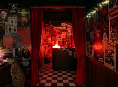 a dark room with red curtains and posters on the wall, lit up by candles