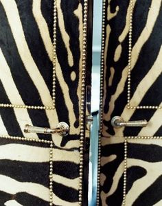 two zebra print doors with metal handles and rivets on each side, both open