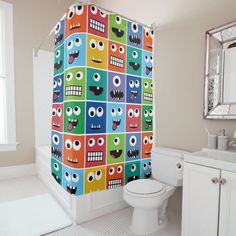 a colorful shower curtain with monster faces on it is in a bathroom next to a toilet