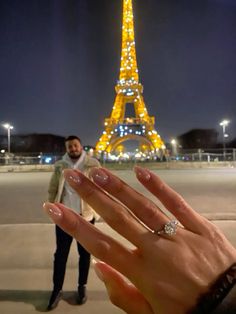 a man and woman standing in front of the eiffel tower with their engagement rings