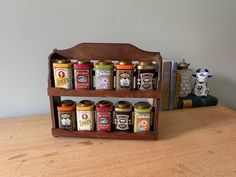 a wooden shelf with spice jars on top of it next to a figurine