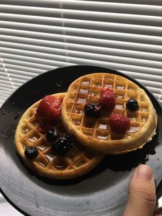 two waffles on a plate with berries and syrup